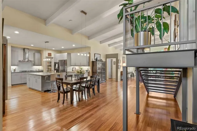 a dining room with stainless steel appliances a dining table chairs and a wooden floor
