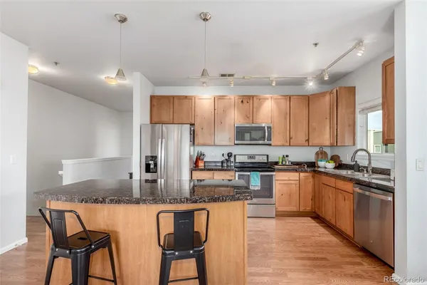 a kitchen with stainless steel appliances granite countertop wooden cabinets a stove a sink a dining table and chairs