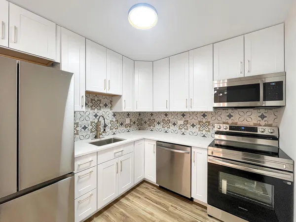 a kitchen with white cabinets and stainless steel appliances