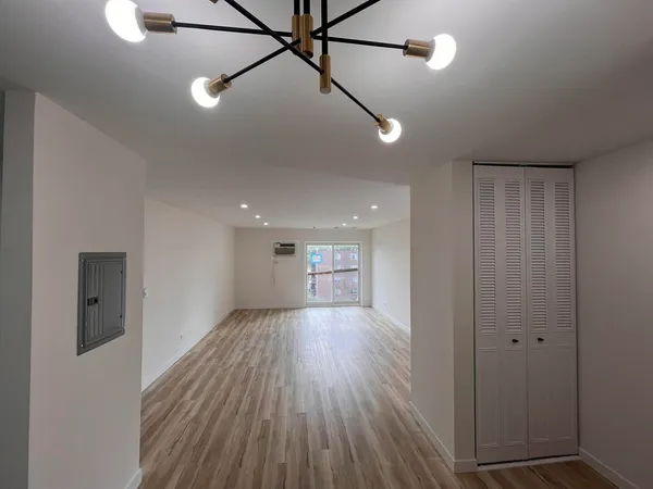 a view of an empty room with wooden floor and a window
