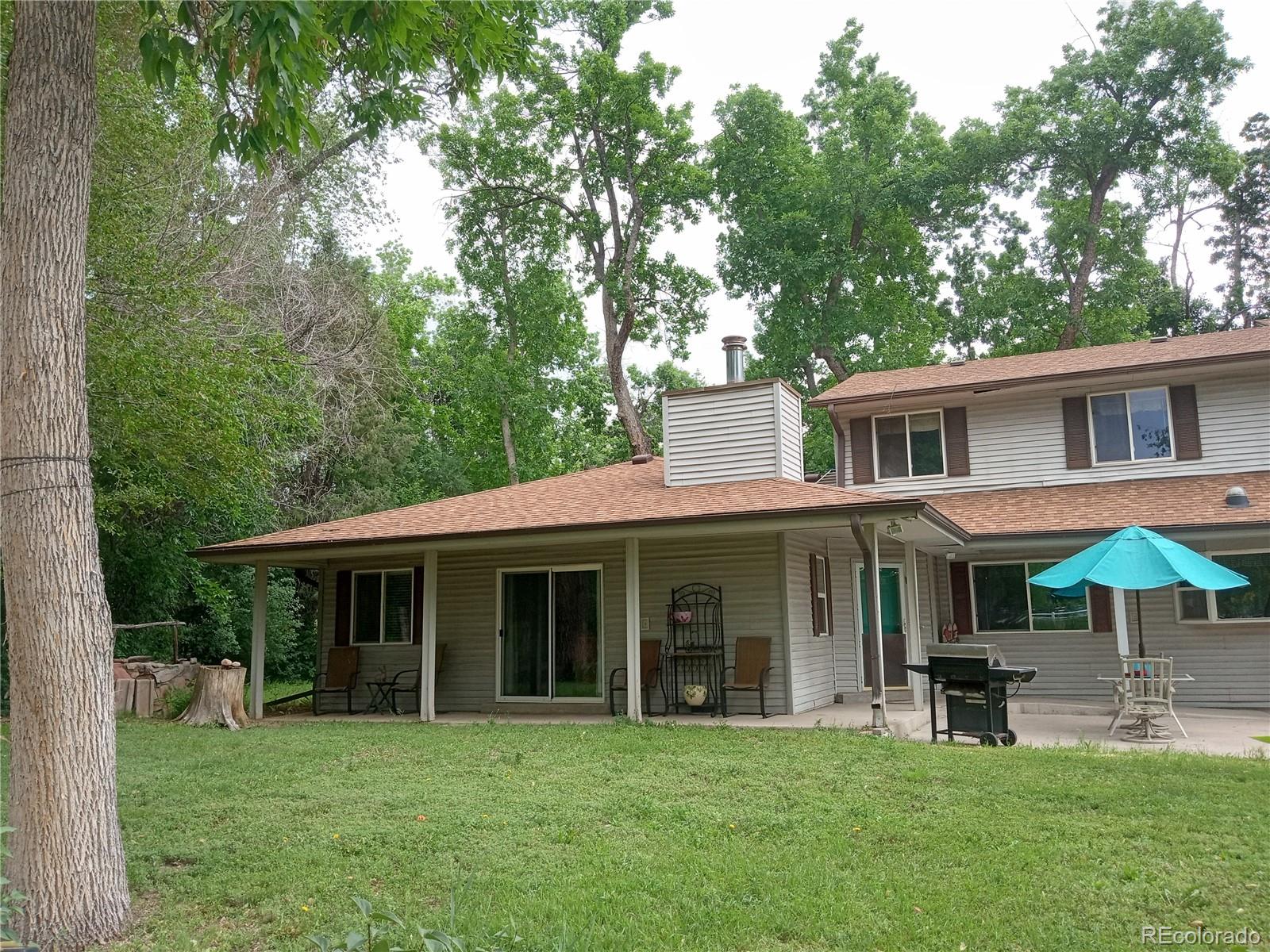 7150 South Platte Canyon Road Littleton, CO 80128 - Photo 4 of 37 a view of a white house with a big yard and potted plants and large trees