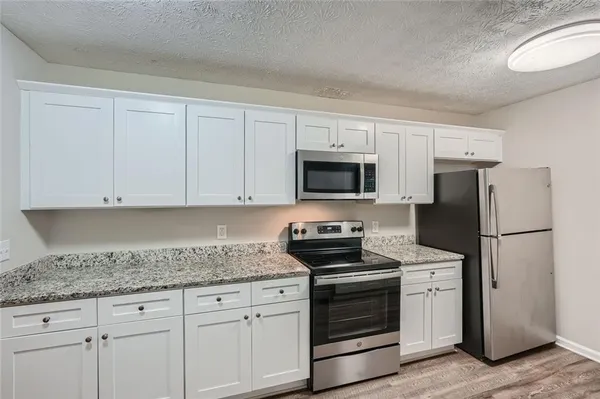 a kitchen with granite countertop white cabinets and stainless steel appliances