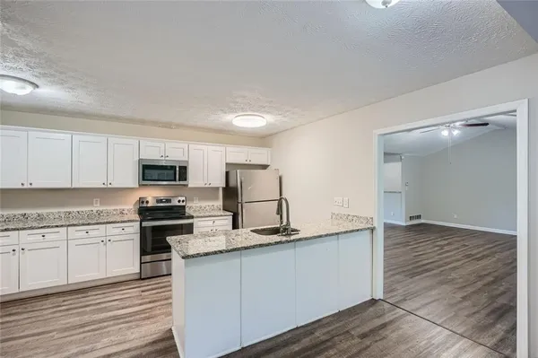 a kitchen with stainless steel appliances granite countertop a stove top oven a sink and white cabinets
