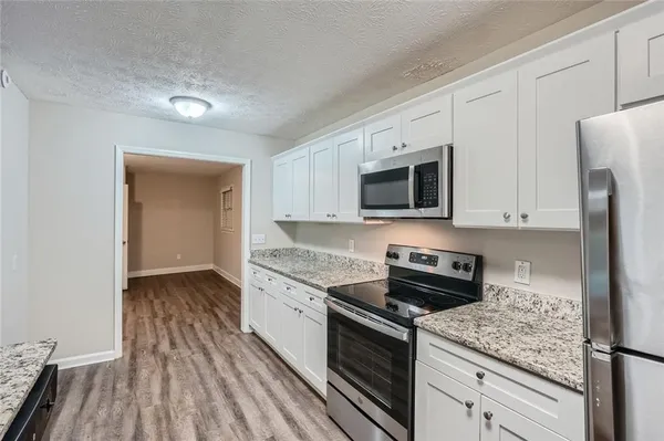 a kitchen with granite countertop a sink stove and refrigerator
