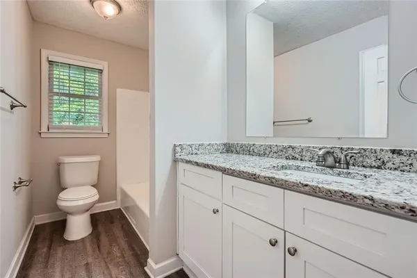 a bathroom with a granite countertop toilet a sink and a mirror
