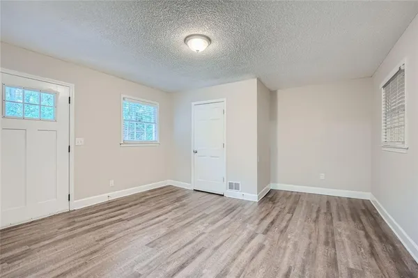 an empty room with wooden floor and windows