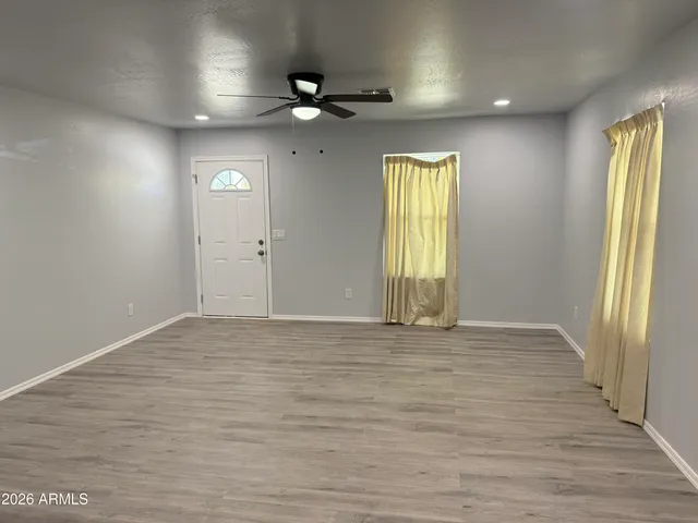 an empty room with wooden floor and windows