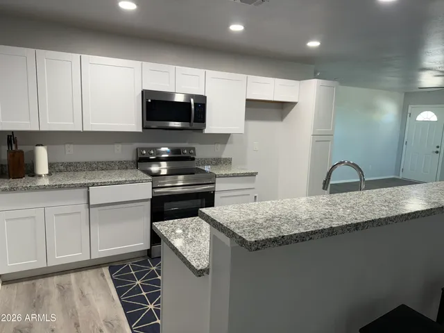 a kitchen with granite countertop a sink a stove and cabinets