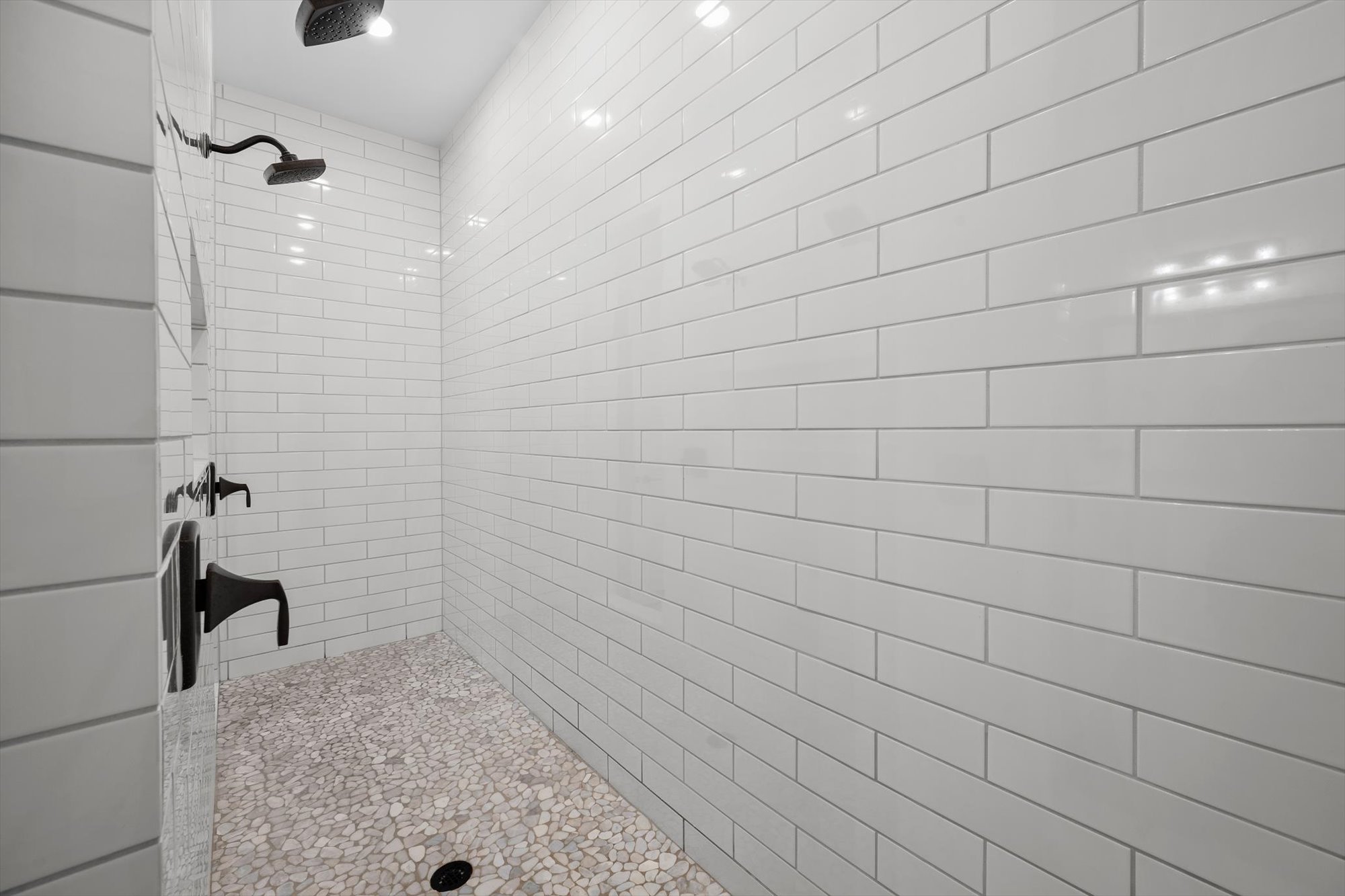 638 Strada Luca Florence, TX 76527 - Photo 16 of 38 A spacious shower with textured pebble flooring complements sleek white subway tiles and modern fixtures.