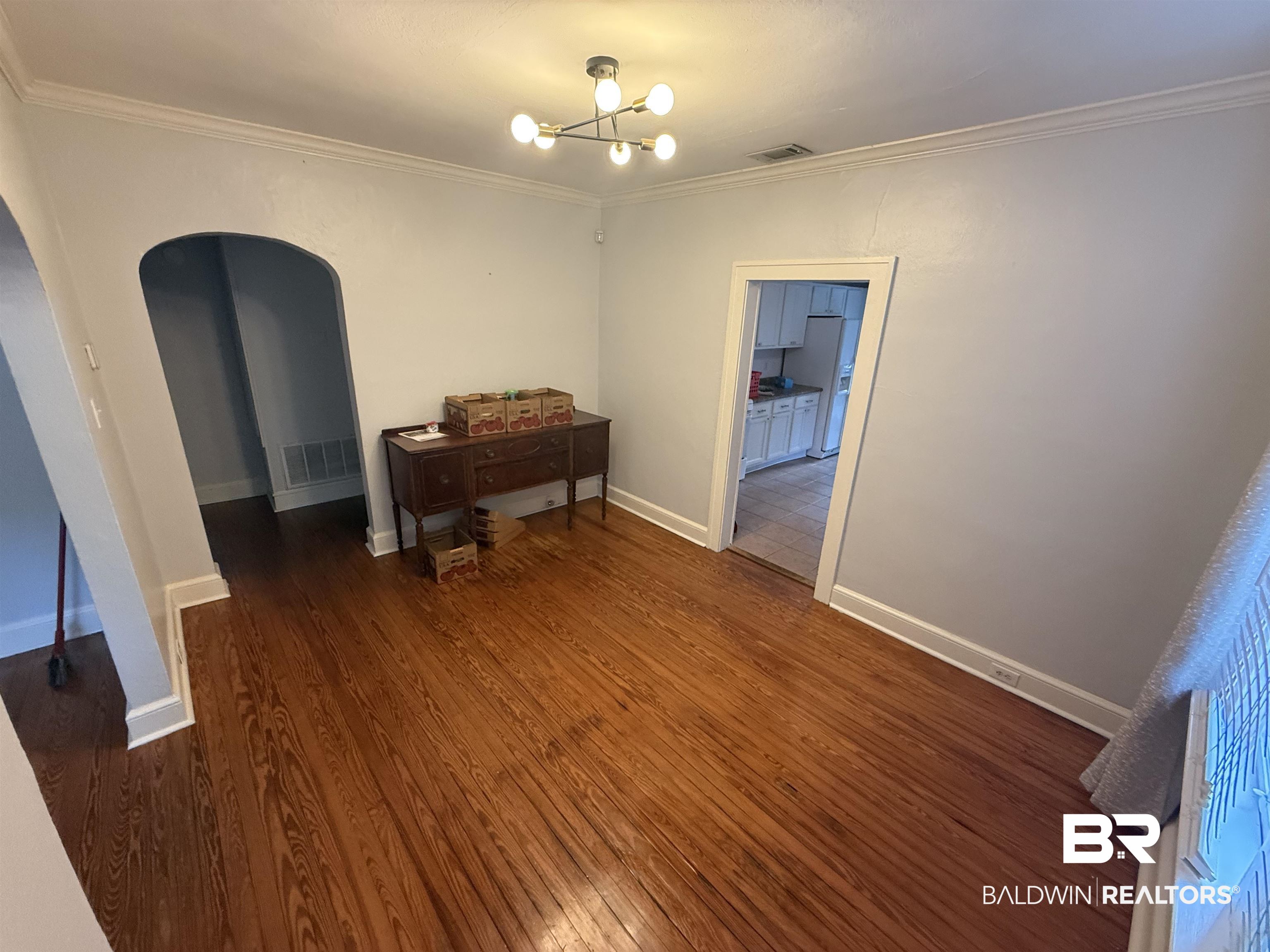 266 Westwood Street Mobile, AL 36606 - Photo 32 of 34 Spare room featuring arched walkways, wood finished floors, a chandelier, and ornamental molding