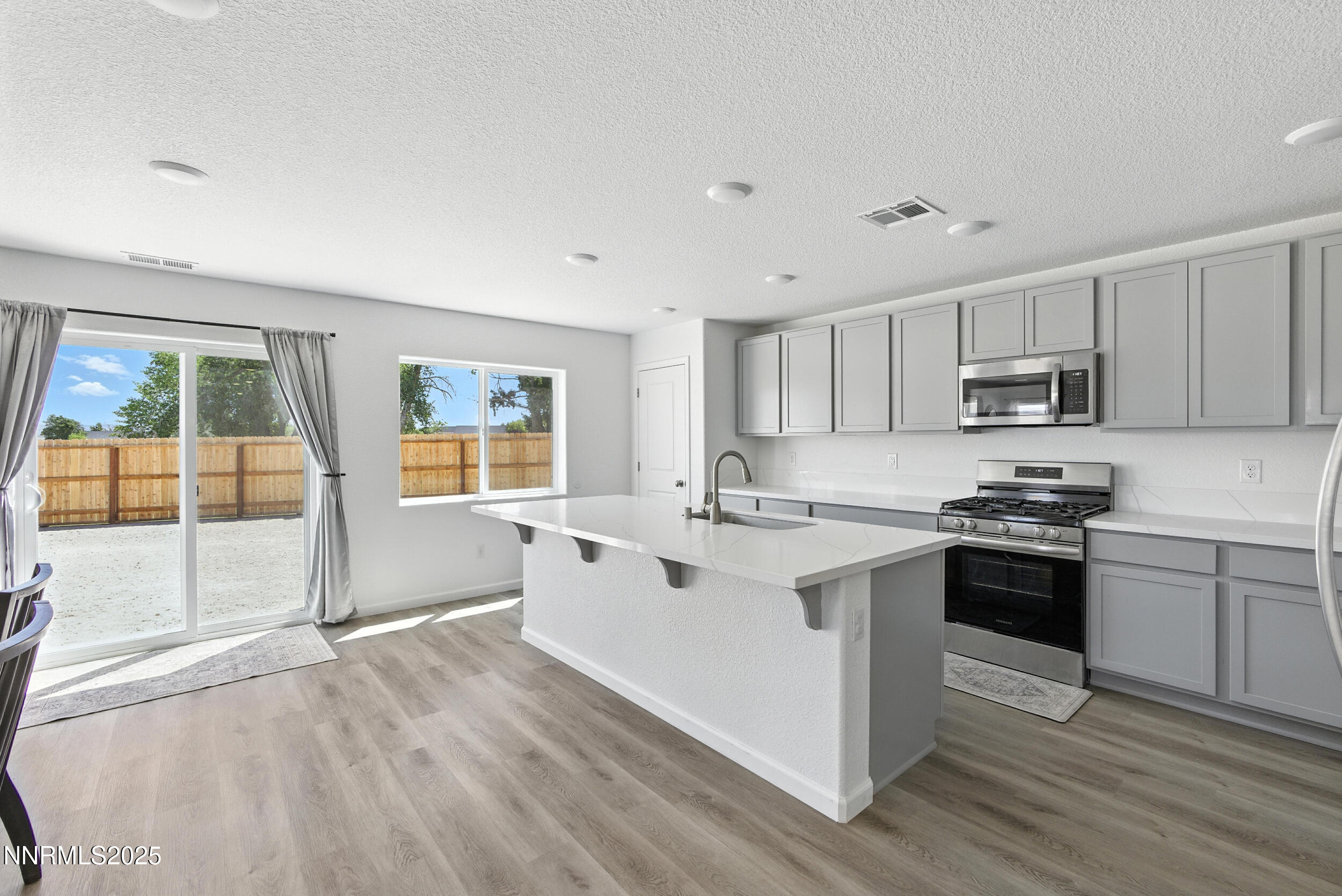 6778 Shell Court Fernley, NV 89408 - Photo 11 of 33 a kitchen with stainless steel appliances granite countertop a stove top oven a sink dishwasher a refrigerator and white cabinets with wooden floor