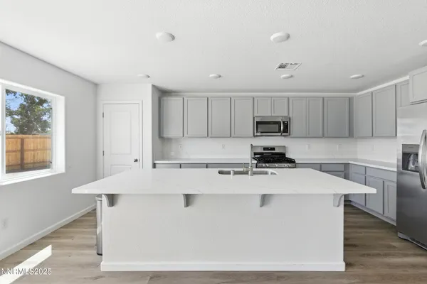 a kitchen with stainless steel appliances granite countertop a stove top oven a sink dishwasher a refrigerator and white cabinets with wooden floor