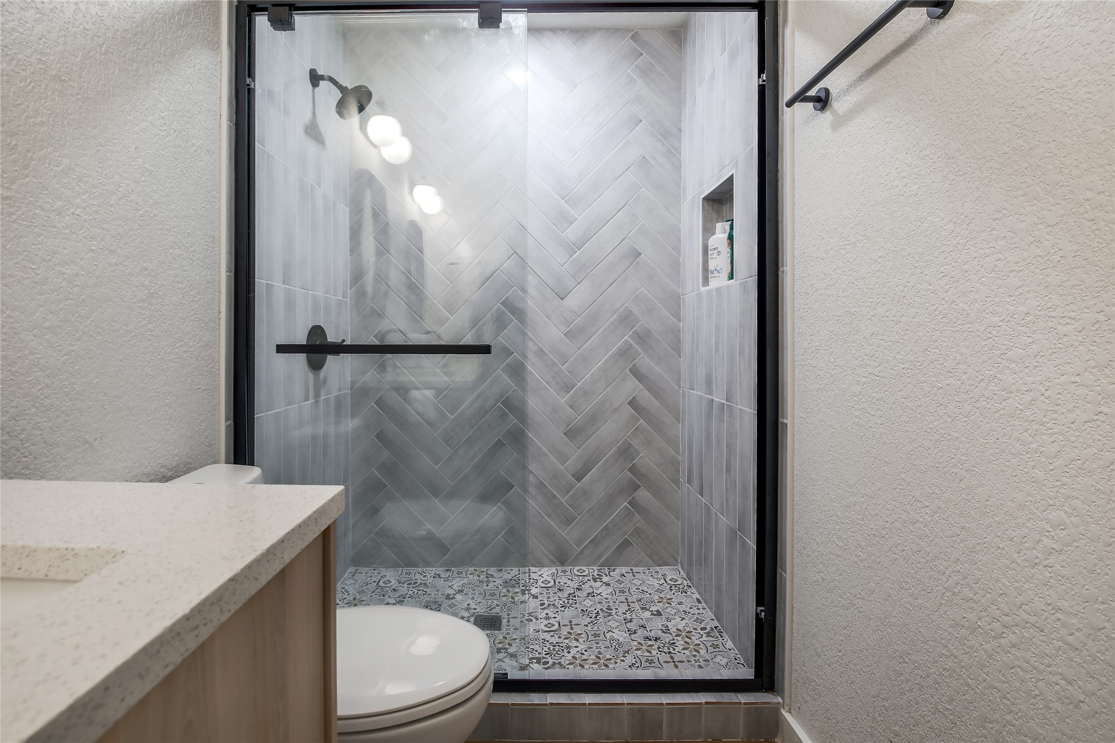 10509 Macmora Road, Unit A Austin, TX 78758 - Photo 10 of 17 A well-appointed shower stall features striking herringbone wall tile and an ornate patterned floor.