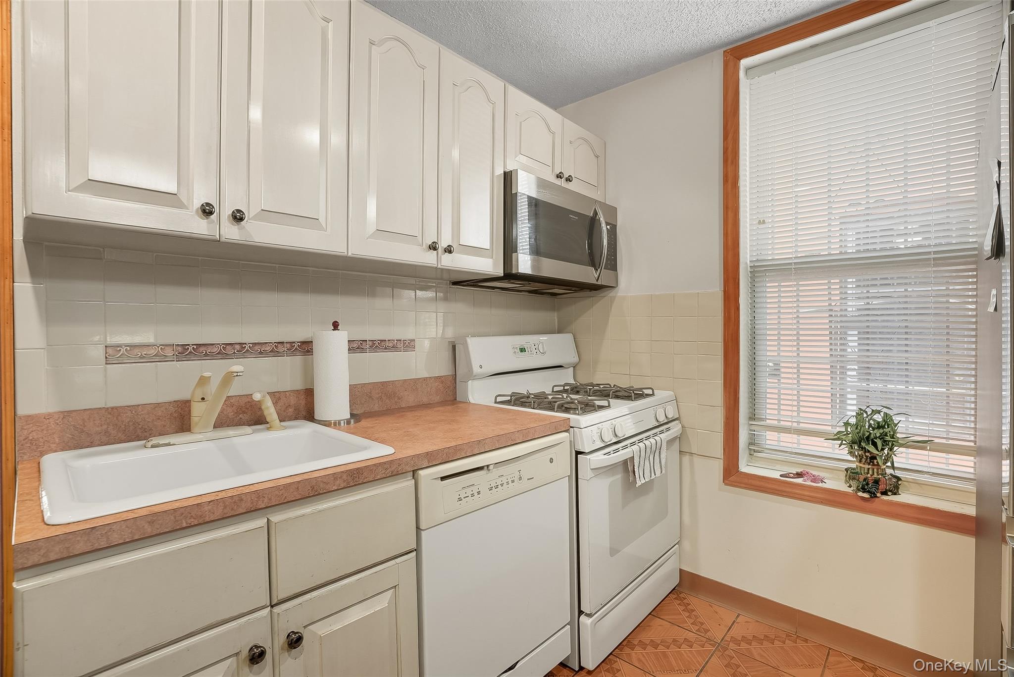 1036 Metcalf Avenue Bronx, NY 10472 - Photo 5 of 26 a kitchen with stainless steel appliances granite countertop a sink a stove and white cabinets