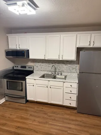 a kitchen with granite countertop white cabinets and black appliances