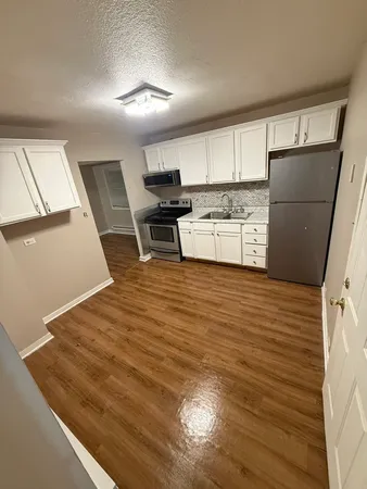 a kitchen with granite countertop a refrigerator and a stove top oven
