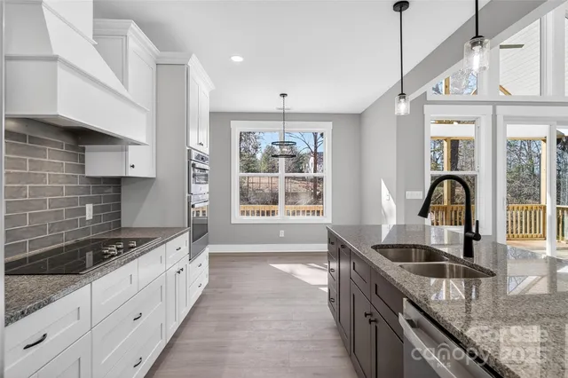 a kitchen with granite countertop a sink stainless steel appliances a window and cabinets
