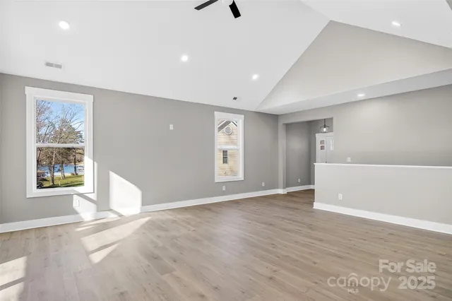 a view of an empty room with window and wooden floor