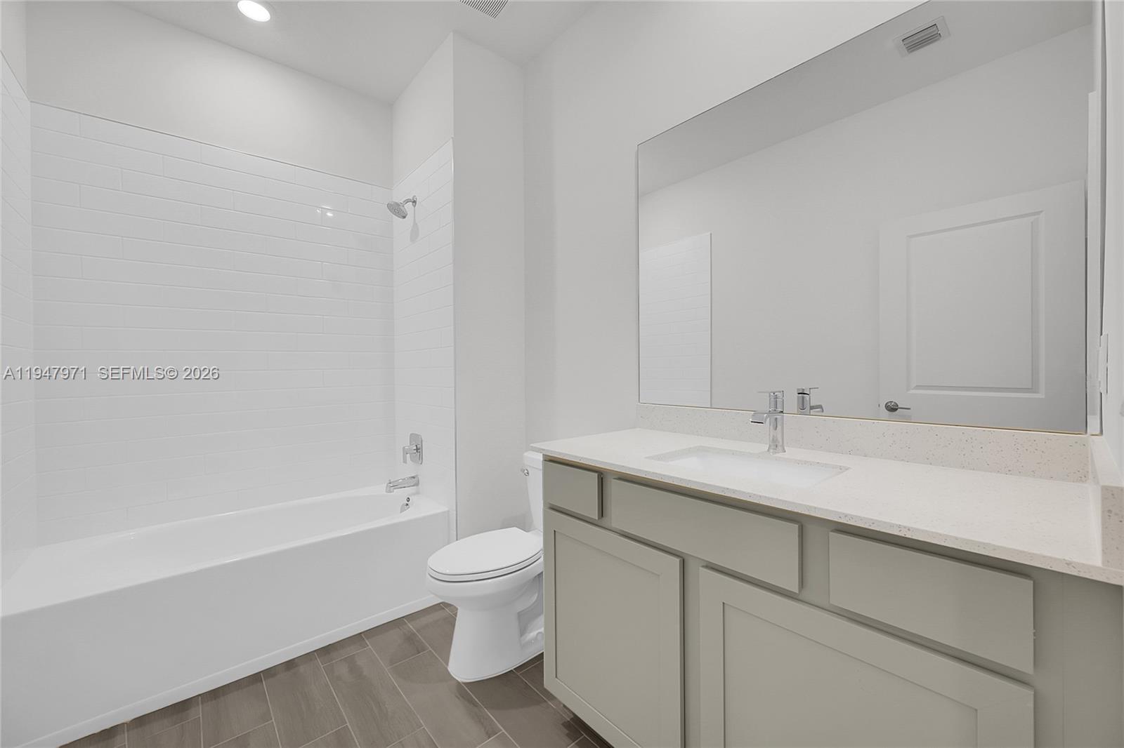 19465 Whispering Creek Road Loxahatchee, FL 33470 - Photo 17 of 22 a bathroom with a granite countertop toilet a sink and bathtub