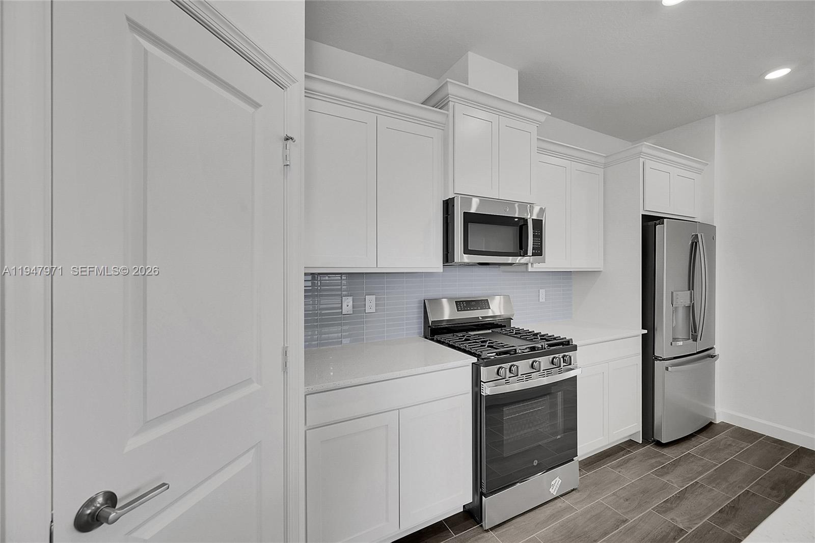 19465 Whispering Creek Road Loxahatchee, FL 33470 - Photo 7 of 22 a kitchen with white cabinets and stainless steel appliances