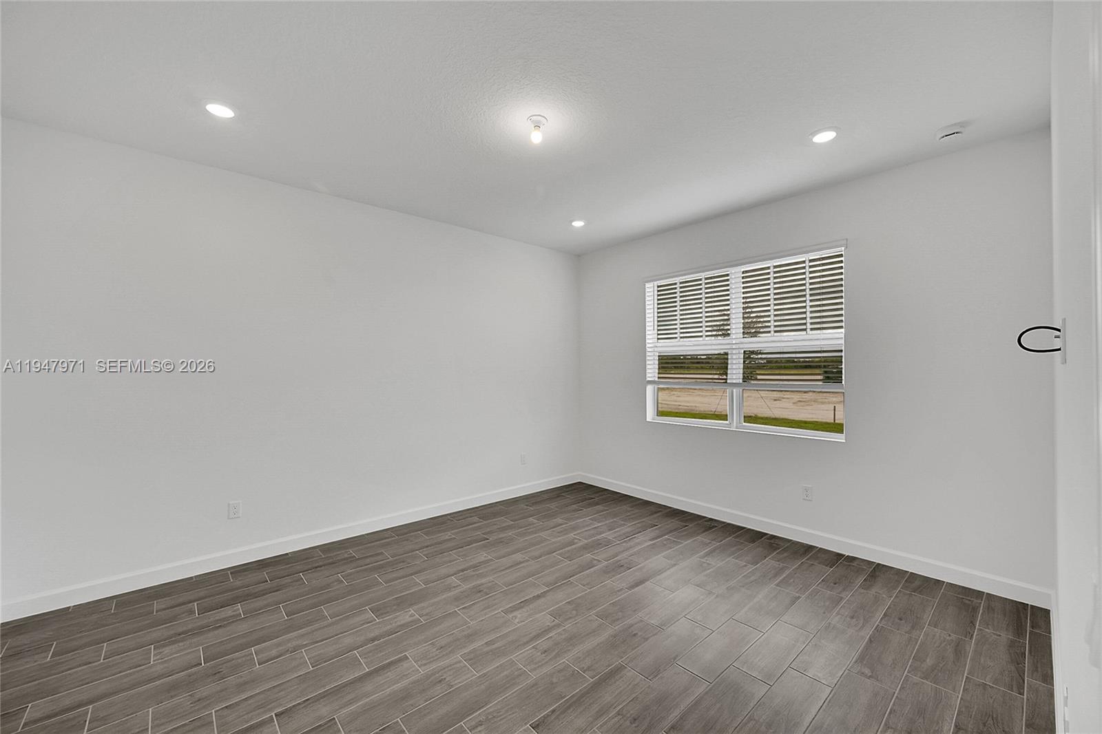 19465 Whispering Creek Road Loxahatchee, FL 33470 - Photo 9 of 22 an empty room with wooden floor and windows