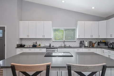 a kitchen with granite countertop a sink a stove a window and cabinets