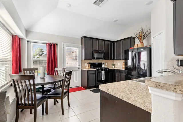 a kitchen with stainless steel appliances kitchen island granite countertop a table chairs and a refrigerator