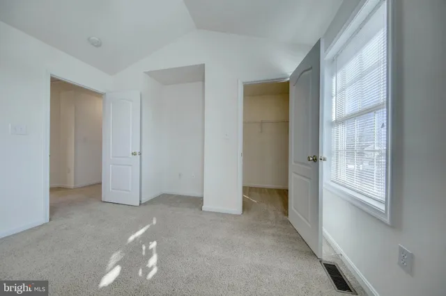 a view of an empty room with closet and wooden door