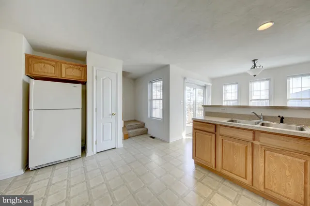 a large white kitchen with a sink and a refrigerator