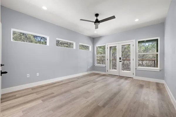 a view of an empty room with a window and wooden floor