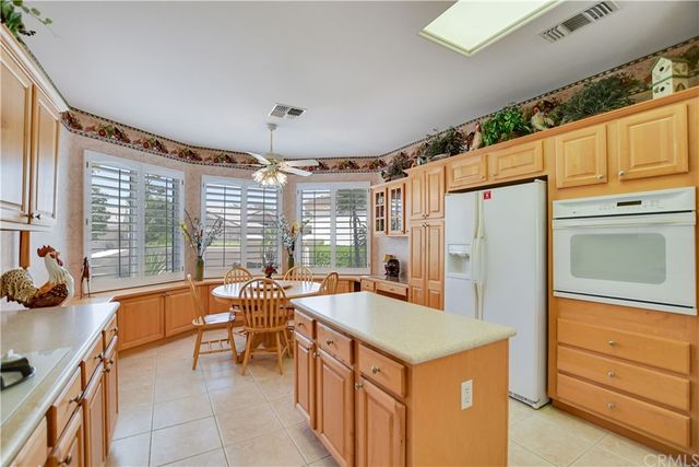 a kitchen with stainless steel appliances granite countertop a refrigerator a stove a sink dishwasher and white cabinets with wooden floor