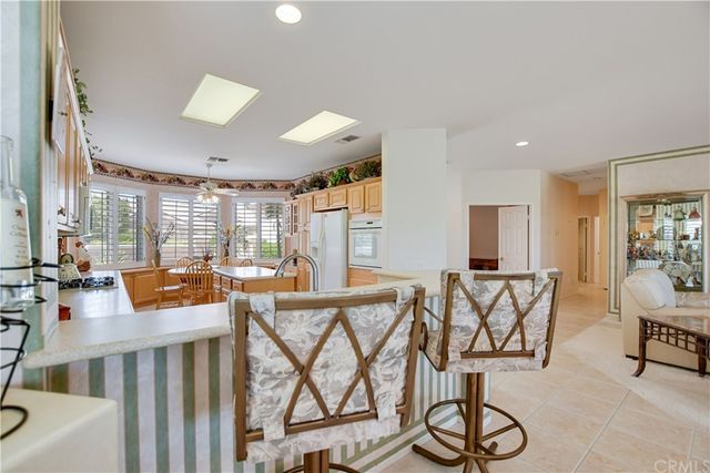 a kitchen with a stove a sink a counter top space and living room area