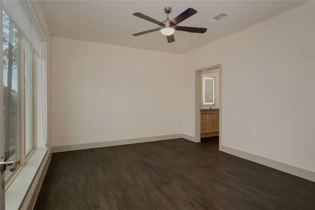 an empty room with wooden floor and a ceiling fan