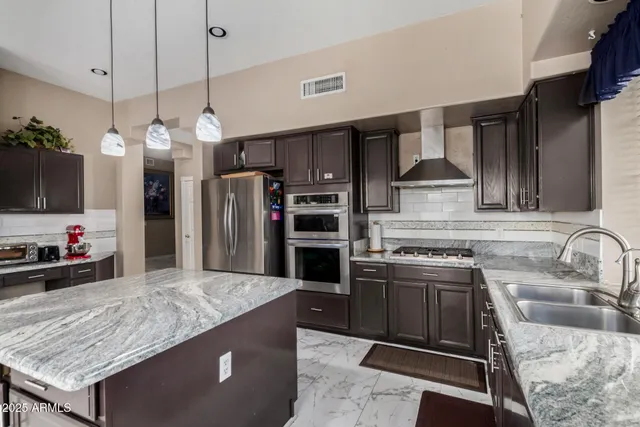 a kitchen with stainless steel appliances granite countertop a sink a stove and a refrigerator