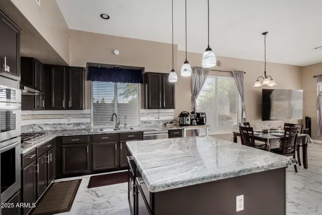 a kitchen with kitchen island granite countertop a sink a counter top space and cabinets