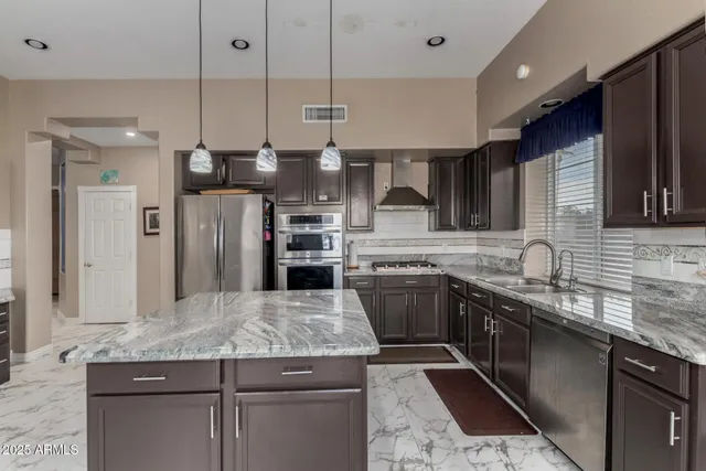 a kitchen with stainless steel appliances granite countertop a sink a stove and a refrigerator