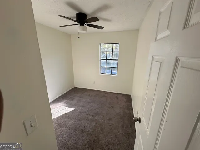an empty room with windows and fan