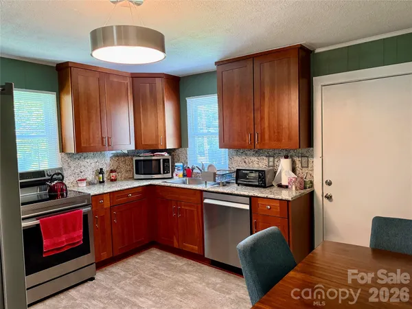 a kitchen with stainless steel appliances granite countertop a sink dishwasher stove and cabinets with wooden floor