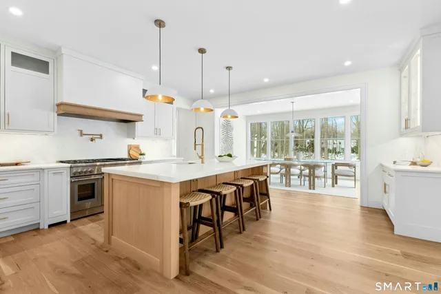 a large kitchen with stainless steel appliances kitchen island granite countertop a sink a counter space and a window