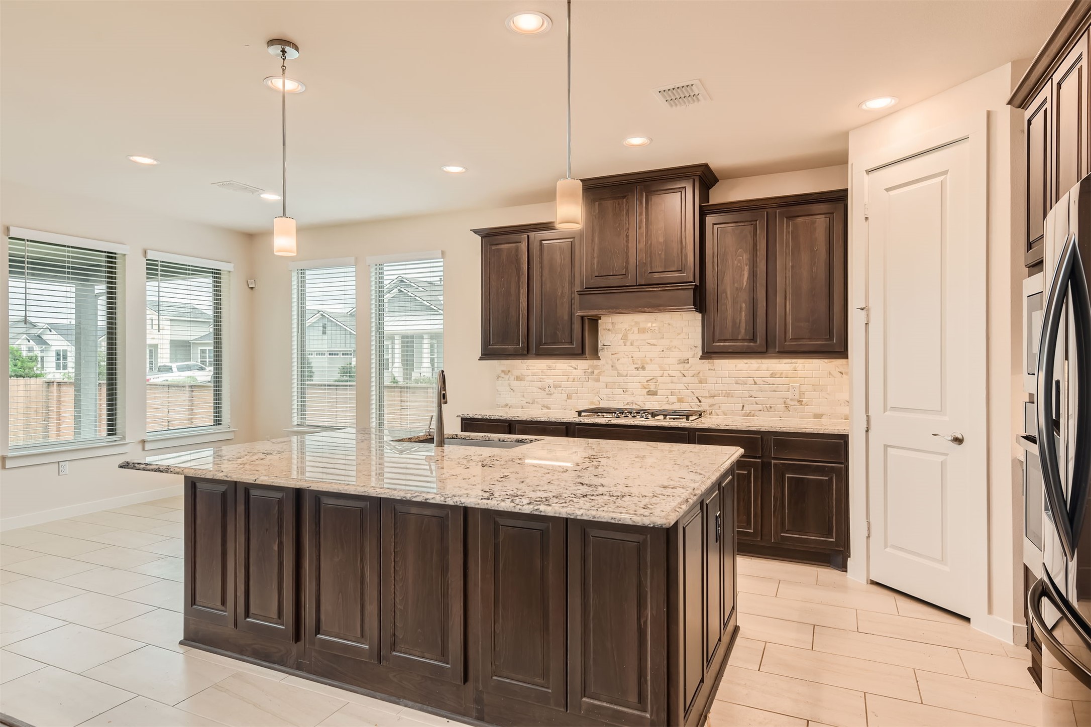 8313 Spire View Austin, TX 78744 - Photo 11 of 33 A generously sized central island with granite countertops anchors this well-lit, open-concept kitchen.