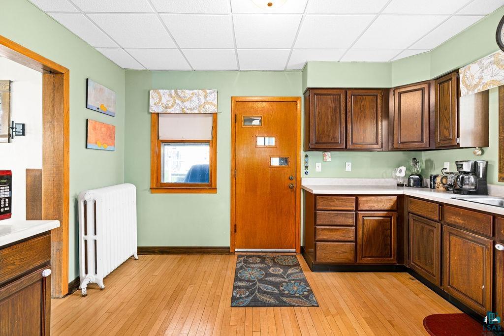 23 5th Street Proctor, MN 55810 - Photo 15 of 32 Kitchen featuring a paneled ceiling, radiator, and light hardwood / wood-style flooring