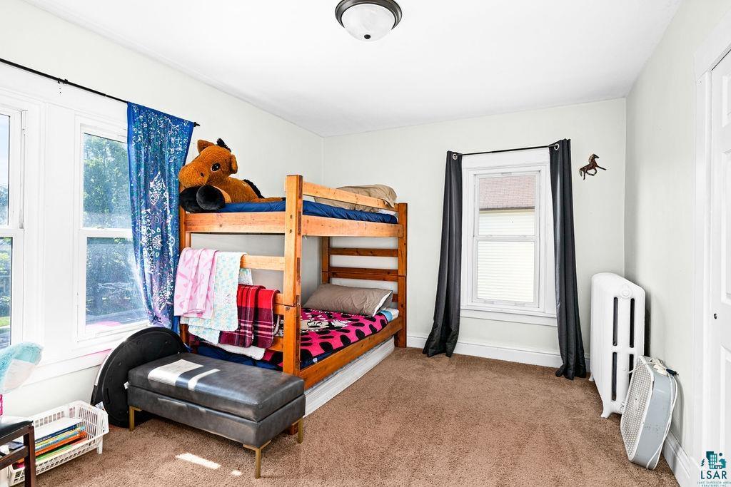 23 5th Street Proctor, MN 55810 - Photo 18 of 32 Carpeted bedroom featuring radiator heating unit and multiple windows