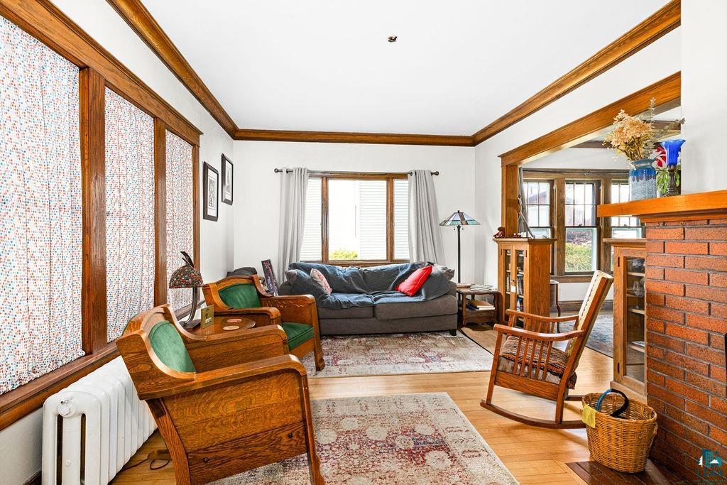 23 5th Street Proctor, MN 55810 - Photo 8 of 32 Living room with light wood-type flooring, a fireplace, radiator heating unit, and crown molding