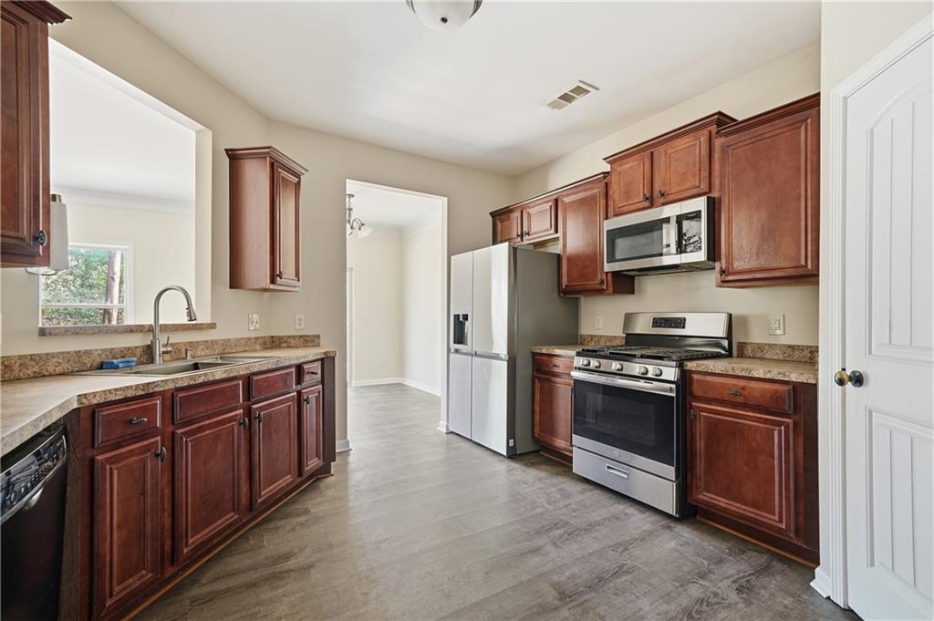404 Sheila Way Canton, GA 30114 - Photo 15 of 36 a kitchen with stainless steel appliances granite countertop a stove top oven a sink dishwasher a refrigerator and a microwave oven with wooden floor