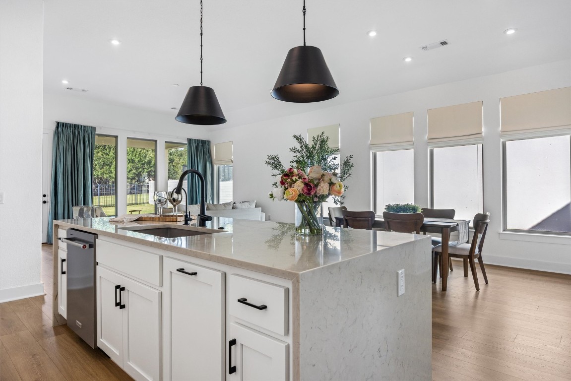 1122 Silver Dollar Trail Georgetown, TX 78628 - Photo 14 of 35 a kitchen with stainless steel appliances granite countertop a stove a sink a dining table and chairs with wooden floor