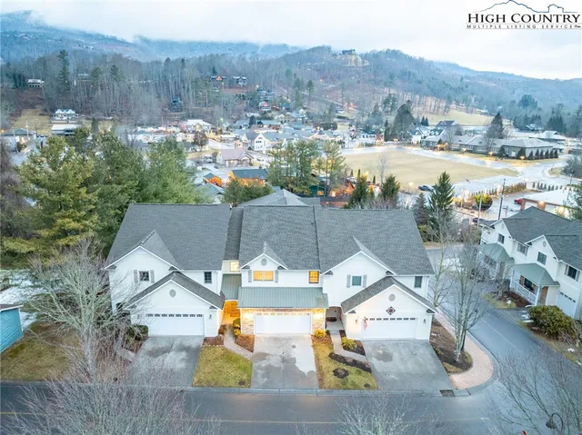 an aerial view of residential houses with outdoor space and parking