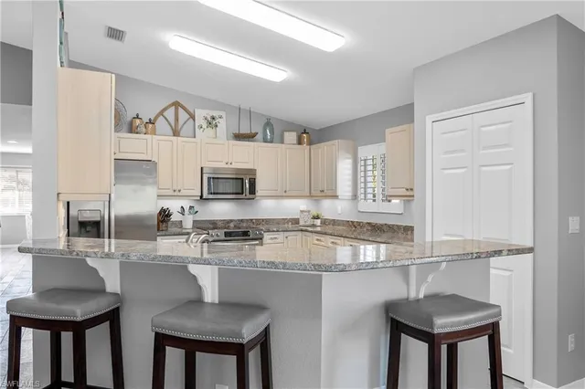 a kitchen with stainless steel appliances granite countertop a table chairs sink and cabinets