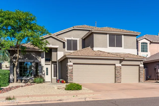 a front view of a house with garage and plants