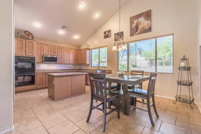 a kitchen with stainless steel appliances granite countertop a stove a sink a refrigerator with a dining table and chairs