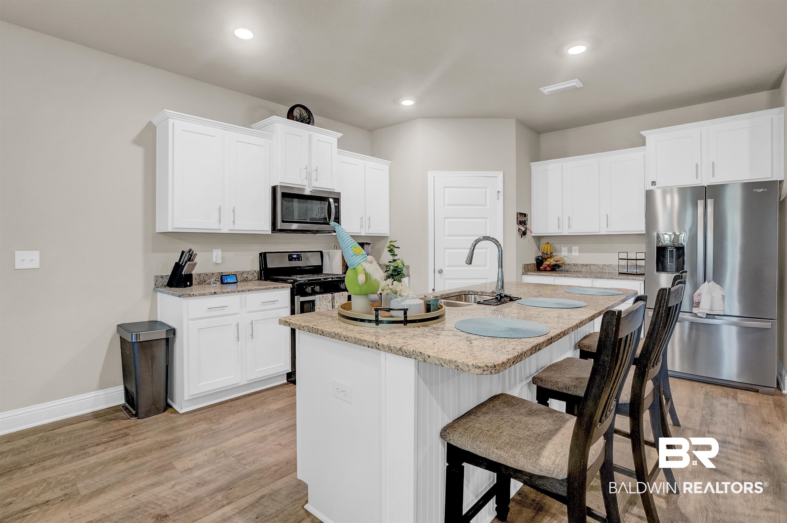 31671 Memphis Loop Daphne, AL 36527 - Photo 23 of 51 Kitchen with white cabinetry, a kitchen bar, a sink, light wood-style flooring, and appliances with stainless steel finishes
